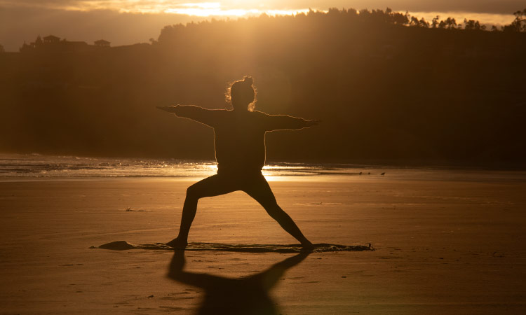 Chica practicando yoga en una playa de la Costa Brava al amanecer