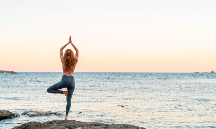 Imagen de chica practicando yoga en l’Escala frente al mar