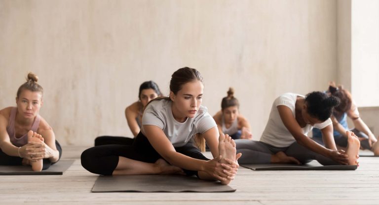 Foto de Grupo de personas practicando postura janu sirsasana en retiro de yoga en la costa brava