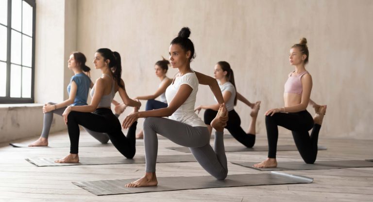 Foto de Grupo de chicas practicando yoga en retiro, postura anjaneyasana