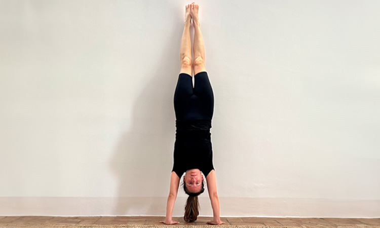 Foto de chica en la postura Adho Mukha Vrksasana, de la secuenca Magic Ten