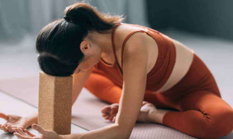 Imagen de una chica practicando una postura en clase de Jivamukti con la ayuda de un bloque de yoga