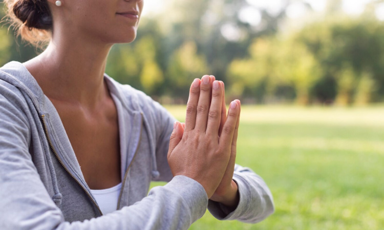 Imagen de una chica con palmas de las manos juntas delante del pecho creando una intención para su práctica de Spiritual Warrior de Jivamukti
