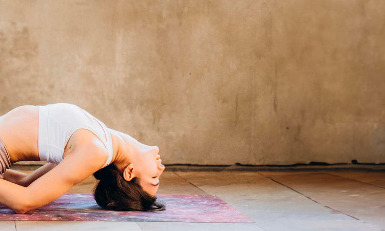 Imagen de una chica practicando Matsyasana, la postura del pez, en una Basic class Jivamukti. Postura de extensión hacia atrás abriendo el pecho.