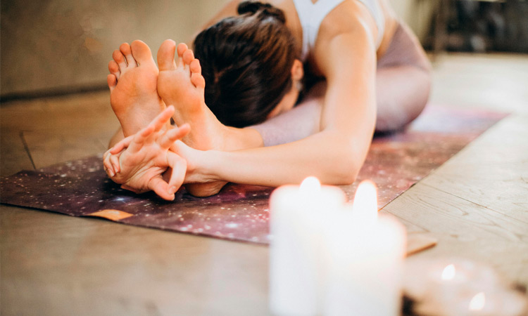 Imagen de una chica en la asana Paschimottanasana en una Basic Class Jivamukti, postura de flexión hacia adelante