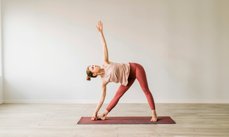 Imagen de un alumna practicando Trikonasana (postura del triángulo) en una clase Beginner Vinyasa de Jivamukti Yoga