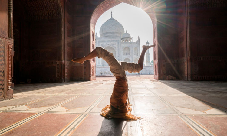 Imagen de una mujer practicando la postura de yoga Sirsasana en un entorno arquitectónico de India