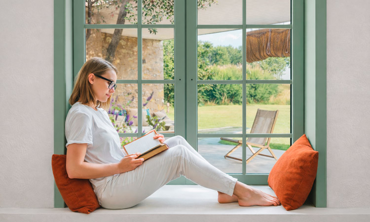 Imagen de una mujer leyendo en un espacio tranquilo durante un retiro de yoga, momento de descanso y conexión personal.