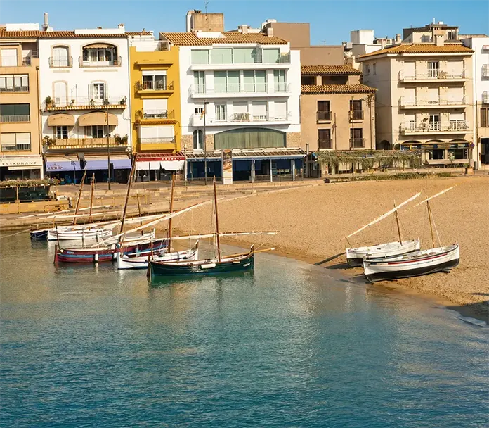 Barcas tradicionales junto a la playa y paseo marítimo de L’Escala, Costa Brava.